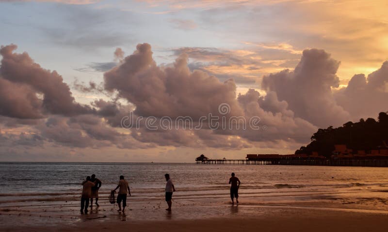 Silhouette of fishermen with fishing nets on a beautiful beach in Langkawi, Malaysia at orange sunset. royalty free stock image Silhouette of fishermen with fishing nets on a beautiful beach in Langkawi, Malaysia at orange sunset. royalty free stock image