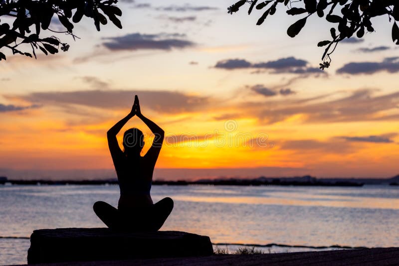 Silhouette gesunde Frau Yoga Gleichgewicht Körper Sport Vitalmeditat und Üben auf dem Felsen im Freien im Strand bei Sonnenunterg
