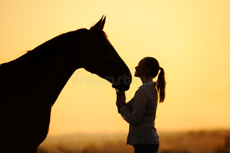 Silhouette of girl with horse at the sunset