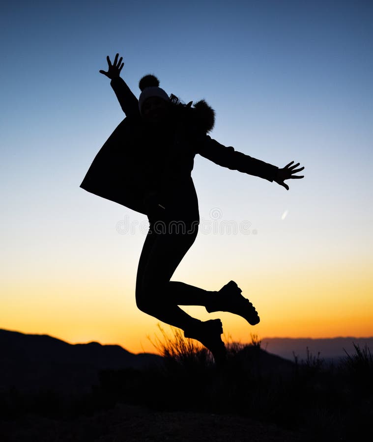 Silhouette of girl jumping in the middle of nature on winter against sunset stock image Silhouette of girl jumping in the middle of nature on winter against sunset stock image