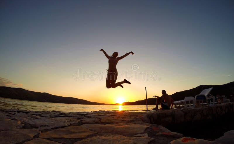 Silhouette of a girl jumping at sunset on the beach