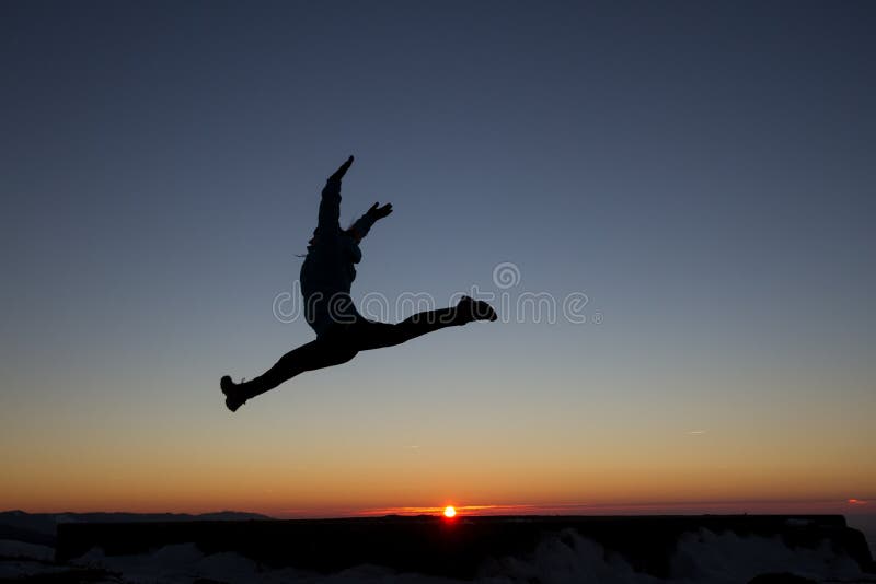 Silhouette of girl jumping in sunset