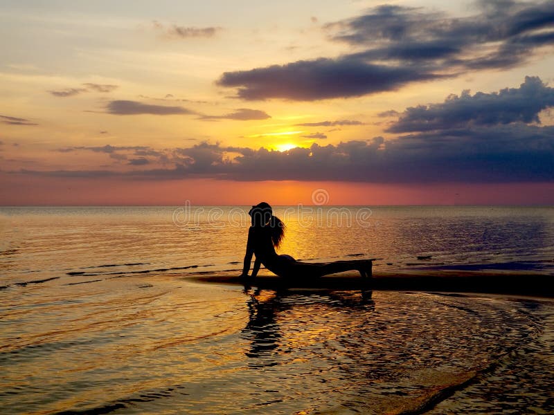 Silhouette of a girl practicing yoga on the beach. Shooting against the sun. Sunset over the sea stock photos Silhouette of a girl practicing yoga on the beach. Shooting against the sun. Sunset over the sea stock photos