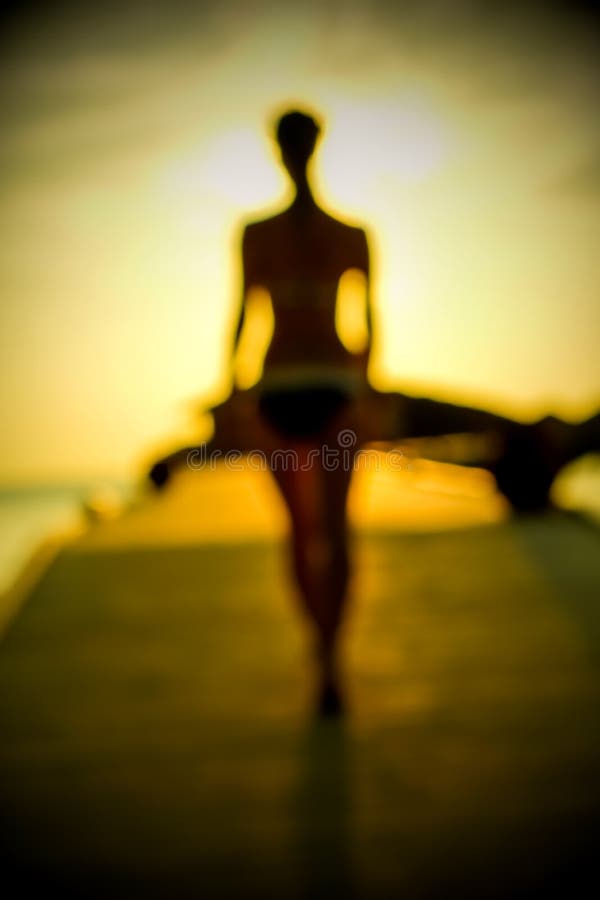 Silhouette of a girl walking along the pier at sunset