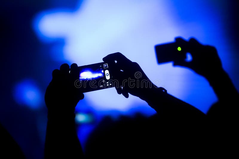 Silueta ruky z davu fotografovanie výkon s modrým fáze svetlá.