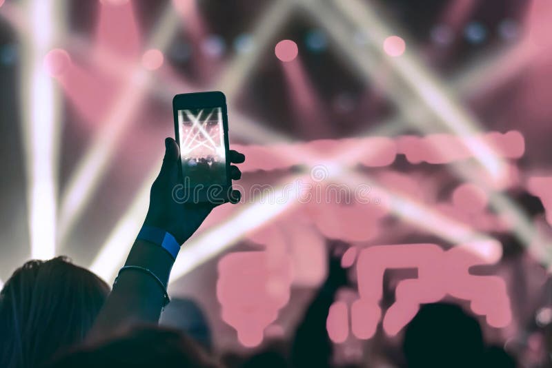 Silhouette of hands with a smartphone at a concert