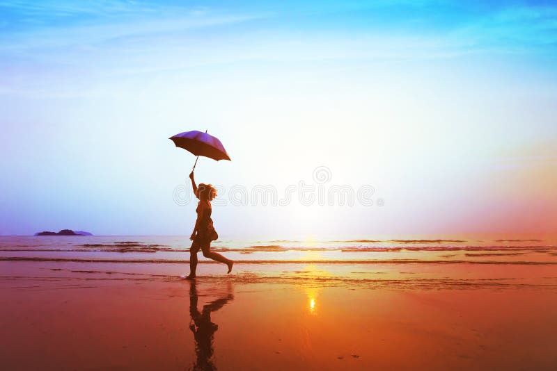 Silhouette of happy carefree girl with umbrella jumping on the beach stock image Silhouette of happy carefree girl with umbrella jumping on the beach stock image