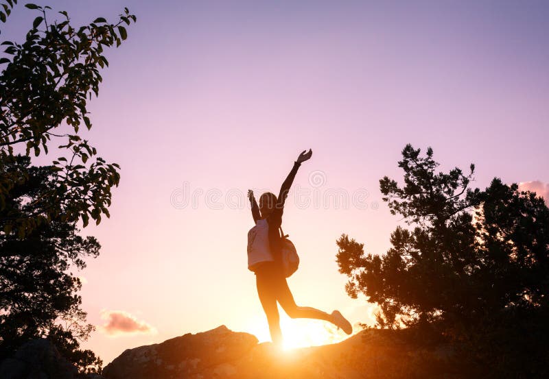Silhouette of a happy young woman in mountains at sunset