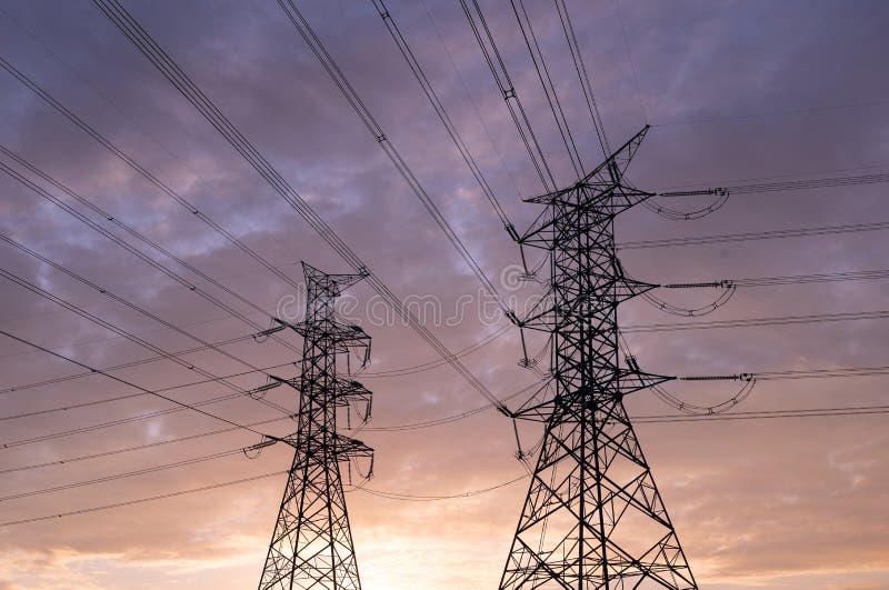 Silhouette of high voltage electric poles and lines, High voltage electric transmission tower at sunset background.