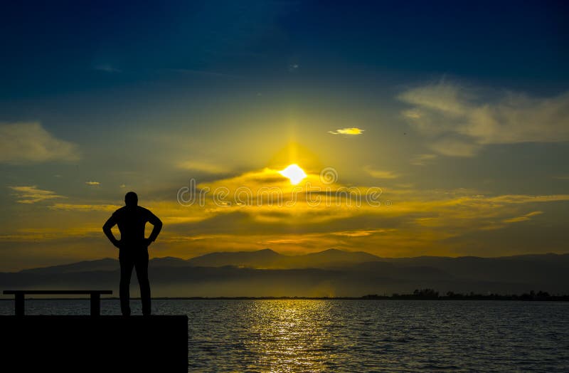 Silhouette, homme seul observant la mer au coucher du soleil images stock Silhouette, homme seul observant la mer au coucher du soleil images stock