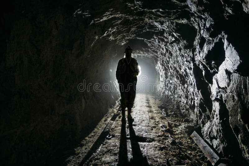 Silhouette humaine rétro-éclairée rampante à l'intérieur du mien abandonné foncé photographie stock libre de droits Silhouette humaine rétro-éclairée rampante à l'intérieur du mien abandonné foncé photographie stock libre de droits
