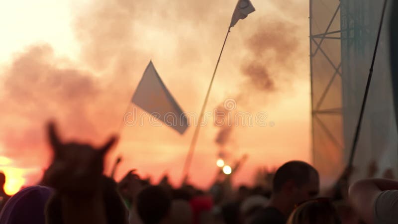 Silhouette händer hos publiken som njuter av konserten Solnedgång och rök vid bergsfestival Tonåringar