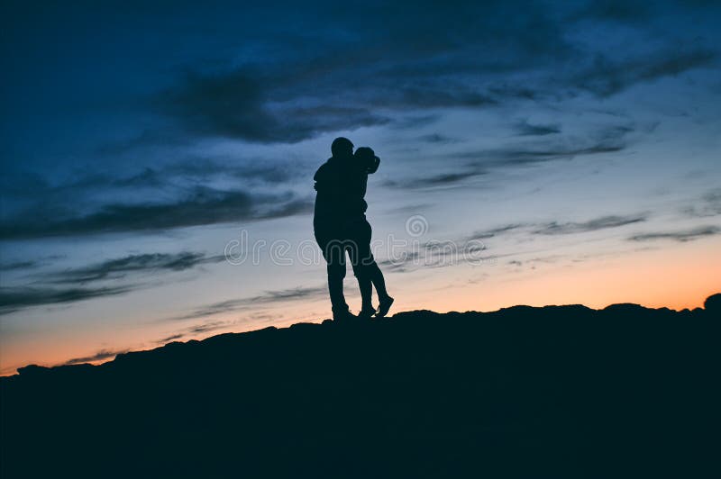 Silhouette of a kissing couple in nature at sunset