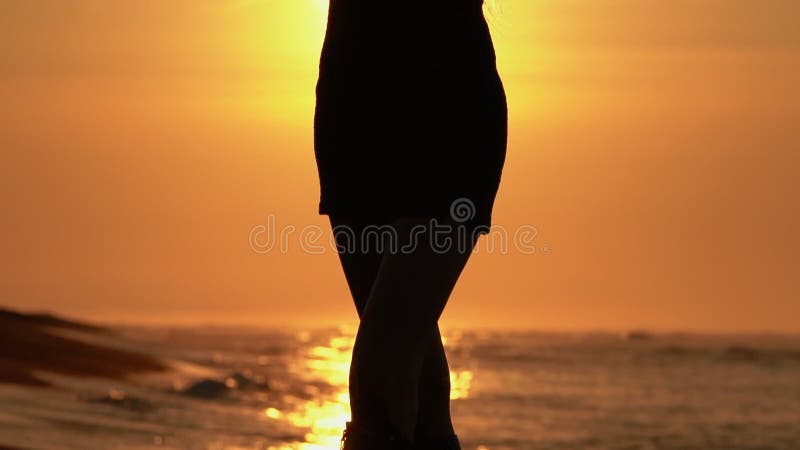 Silhouette-kvinnans skugga på sommardräkt på stranden vid soluppgång