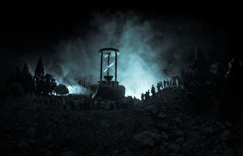 Silhouette of a large crowd of people in forest at night standing against a big hourglass with toned light beams on foggy backgrou royalty free stock photos Silhouette of a large crowd of people in forest at night standing against a big hourglass with toned light beams on foggy backgrou royalty free stock photos