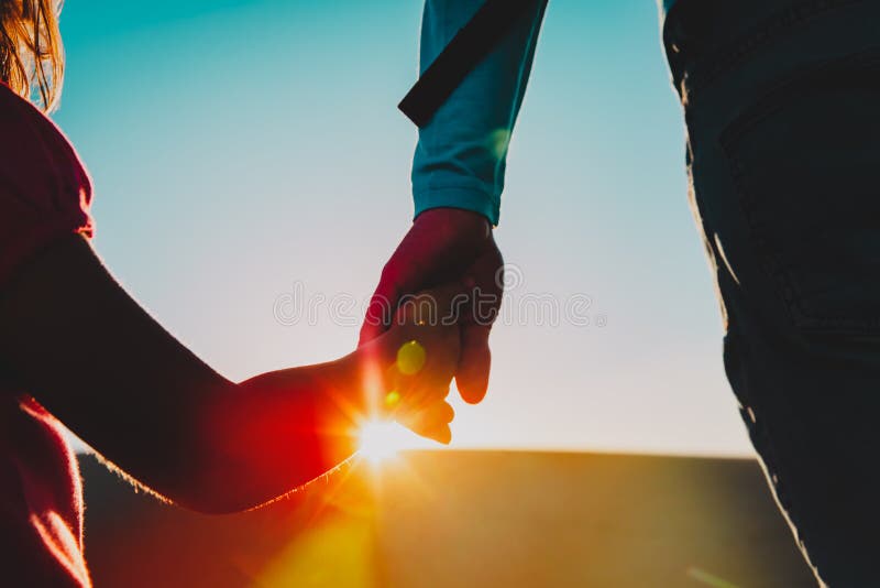 Silhouette of little girl and dad holding hands at sunset, parenting