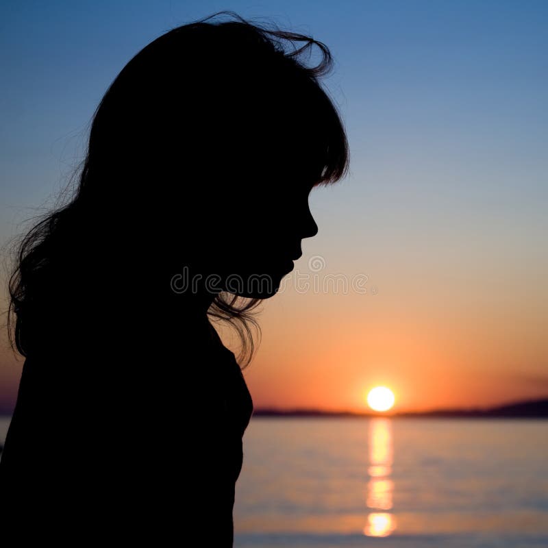 Silhouette of a little girl with sea sunset