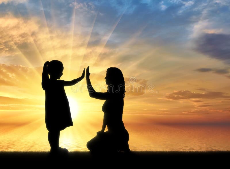 Silhouette, little happy baby girl with mother at the sea on sunset background