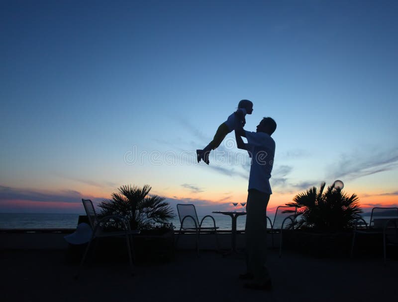 Silhouette of man with child in hands on sunset, summer