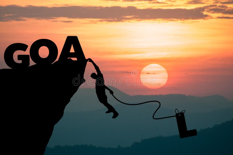 Silhouette Man climbs into cliff to make word GOAL (goal setting concept)