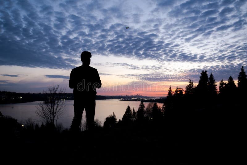 Silhouette of a man controlling a drone that is in the background with the sun setting over downtown Vancouver. royalty free stock images Silhouette of a man controlling a drone that is in the background with the sun setting over downtown Vancouver. royalty free stock images