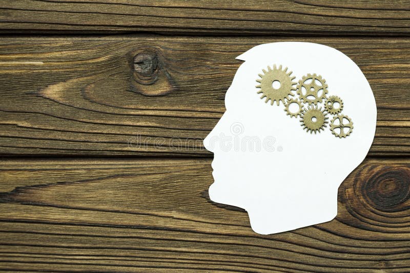 Silhouette of a man`s head with a brain made of iron gears on a wooden background. stock photo Silhouette of a man`s head with a brain made of iron gears on a wooden background. stock photo