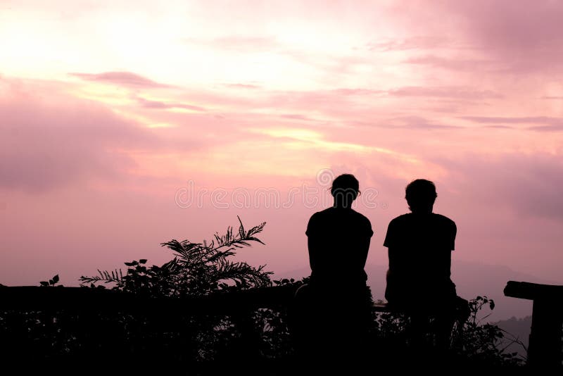 Silhouette Man and woman sitting watch the evening sky at purple sunset