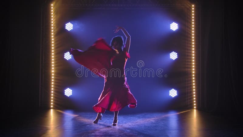 Silhouette mince d'une danseuse danse le flamenco argentin chauffé dans un studio sombre dans le contexte des lumières clips vidéos