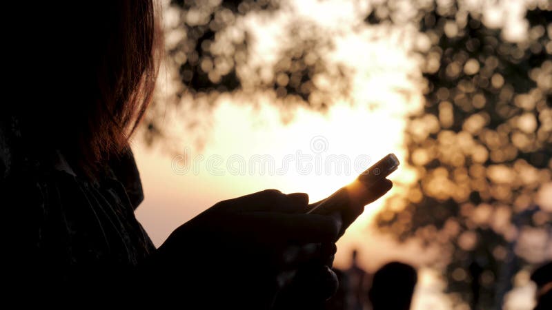 Silhouette oman gebruikt smartphone om te schrijven naar sociale netwerken in sunset
