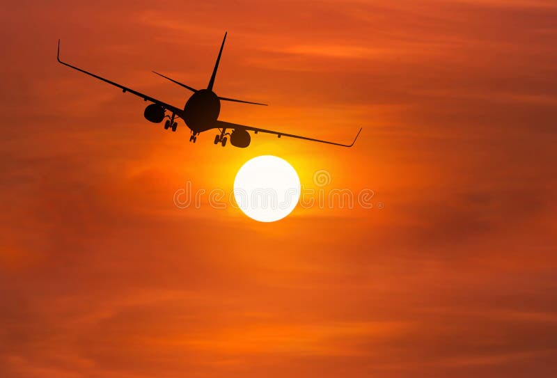 Silhouette passenger airplane flying away in to sky high altitude above the sun during sunset time