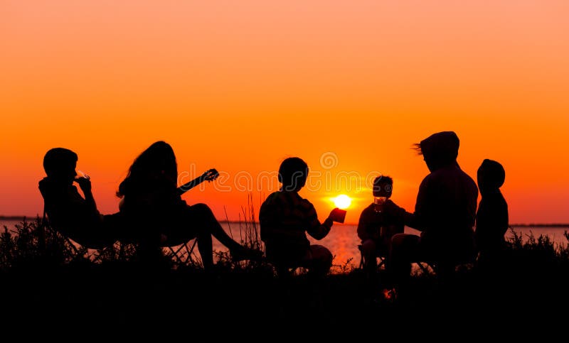 Silhouette of people sitting on the beach with campfire at sunse stock photo Silhouette of people sitting on the beach with campfire at sunse stock photo