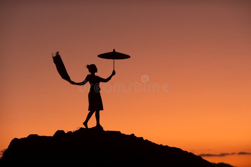 Silhouette picture of a beautiful woman standing in an umbrella on a rock In the middle of the Mekong River