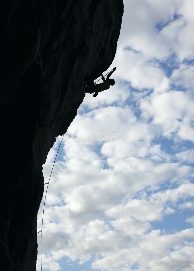 Silhouette of rock climber climbing cliff