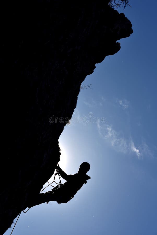 Silhouette of a rock climber hanging on the wall