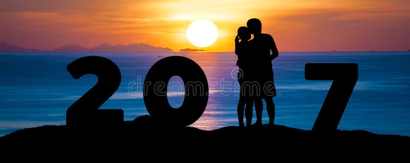 Silhouette of romantic a couple hug kissing against summer sea beach in sunset twilight sky while celebrating happy new year 2017