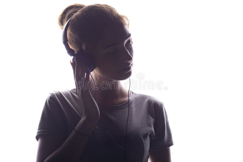 Romantic girl listening to music in headphones, young woman relaxing on a white isolated background