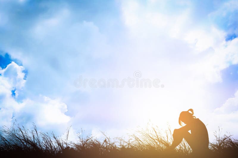 Silhouette of sad a woman depressed sitting alone on meadow.