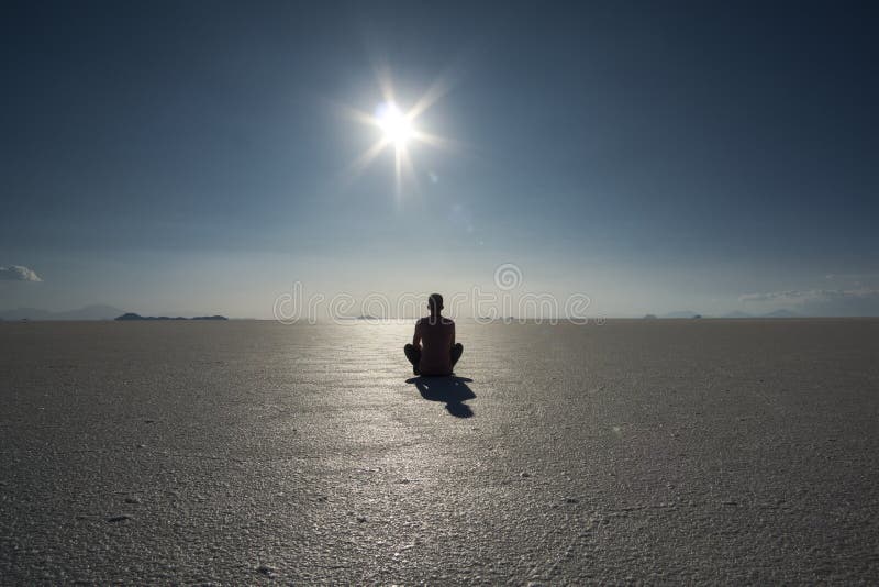 Yoga Silhouette and shadow of a person in bright sunshine and blue sky in the vastness of the dry Salt Flats of Uyuni, Bolivia