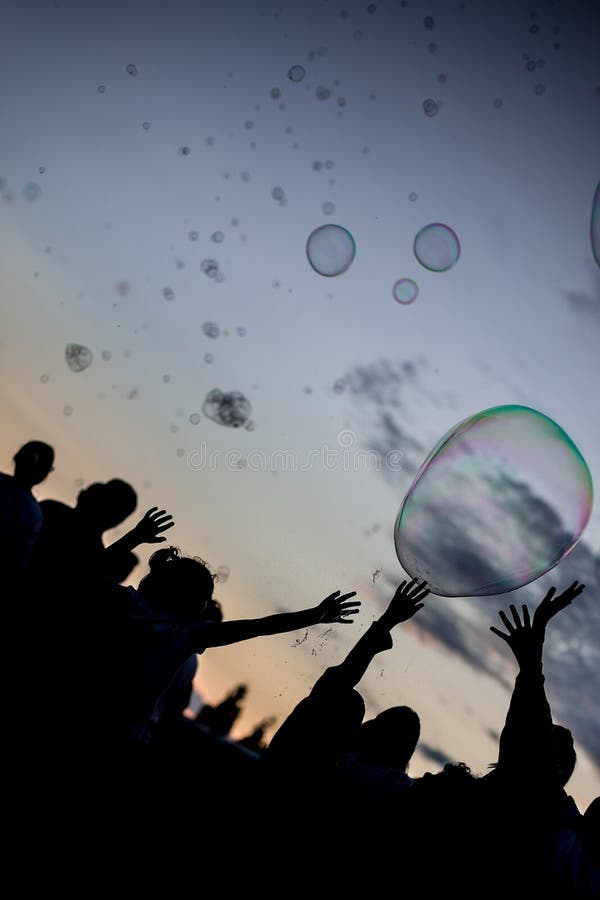 Silhouette shot of people in a bubble party with full of bubbles in a clear blue sky stock photography Silhouette shot of people in a bubble party with full of bubbles in a clear blue sky stock photography