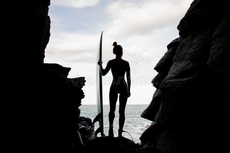 Silhouette slim fit girl in the swimsuit standing with the surf stock image Silhouette slim fit girl in the swimsuit standing with the surf stock image