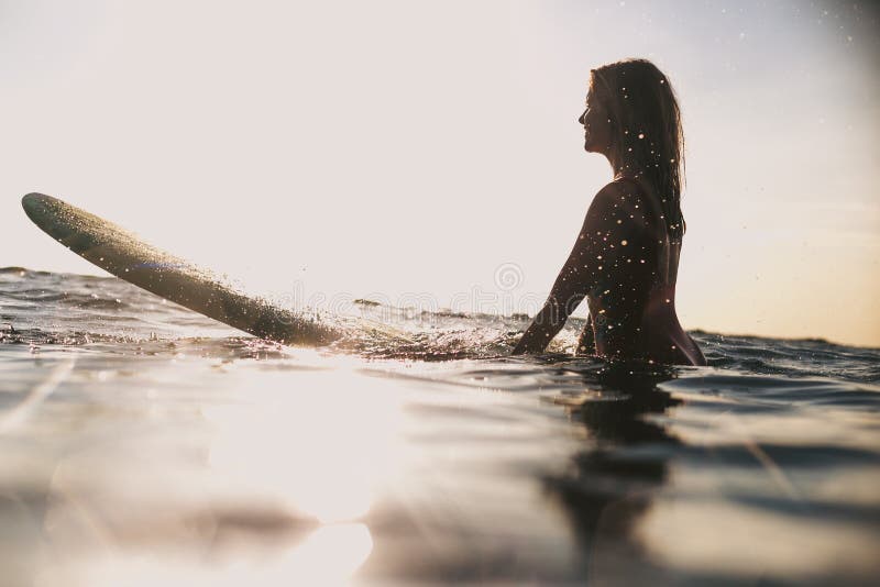 Silhouette of smiling woman with surfing board in ocean royalty free stock photos