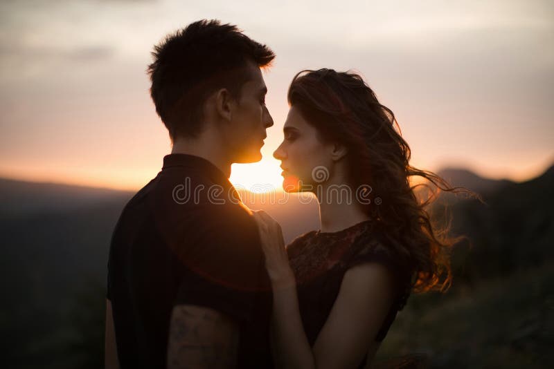Silhouette sweethearts at sunset. Silhouettes of a young couple lovers at sunset in rays of setting sun