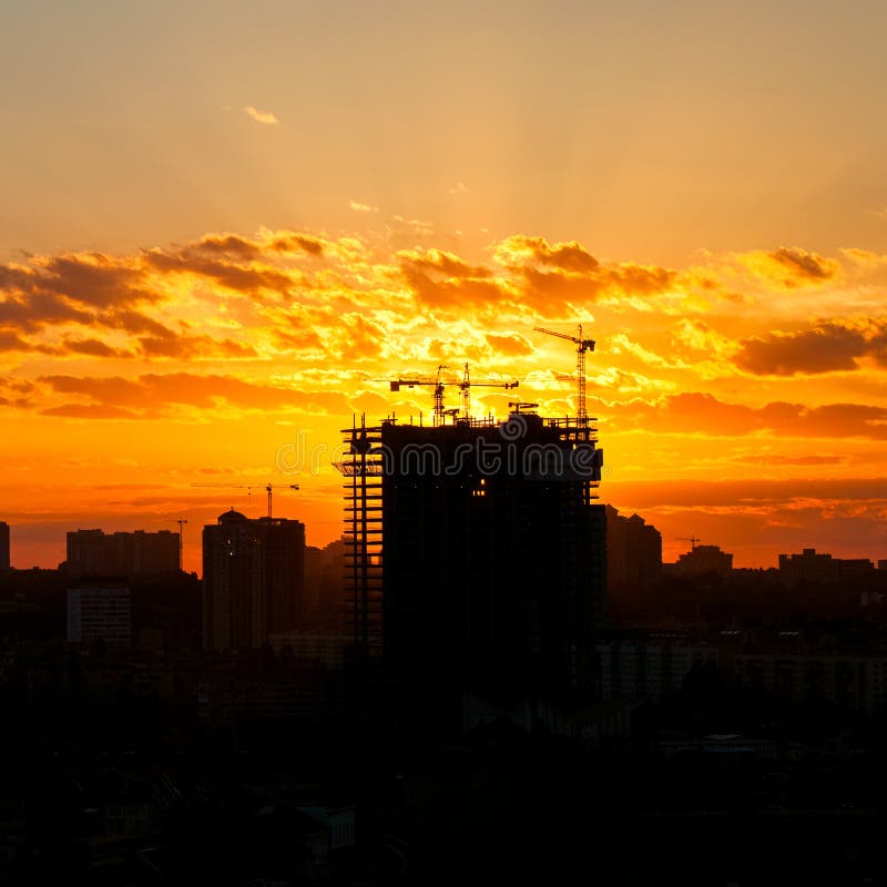 Silhouette of the tower crane on the construction site with city building stock photo Silhouette of the tower crane on the construction site with city building stock photo