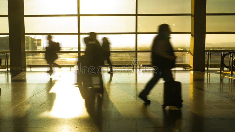 SILHOUETTE: Travelers hurry down airport hall as they try to reach their gate stock images