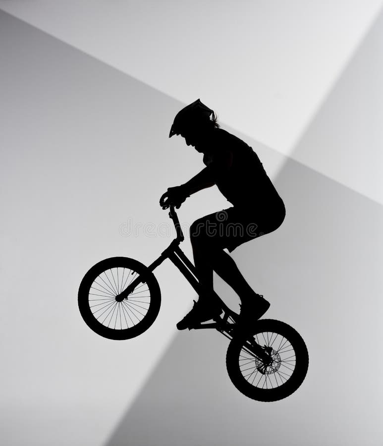 Silhouette Of Trial Biker Sitting On Handlebars Of Bicycle Stock Photo