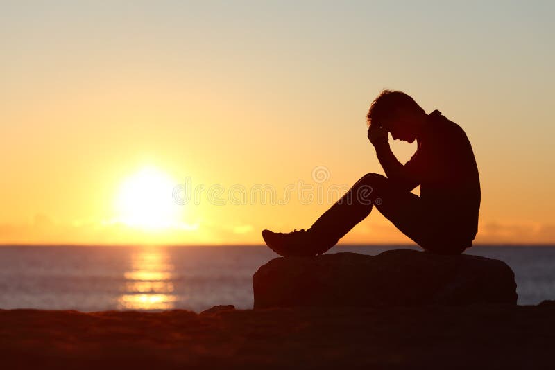 Silhouette triste d'homme inquiétée sur la plage photo libre de droits Silhouette triste d'homme inquiétée sur la plage photo libre de droits