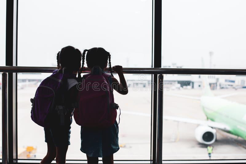 Silhouette of two asian child girls with backpack looking at plane and waiting for boarding in the airport royalty free stock photo Silhouette of two asian child girls with backpack looking at plane and waiting for boarding in the airport royalty free stock photo