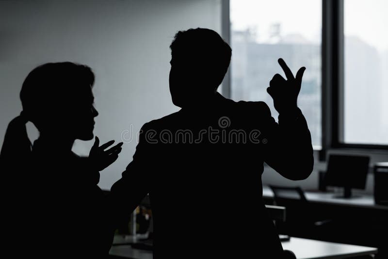 Silhouette of two business people gesturing and arguing in the office