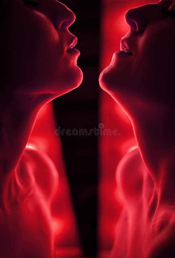 Silhouette of two women face to face. Against the background of bright lamps