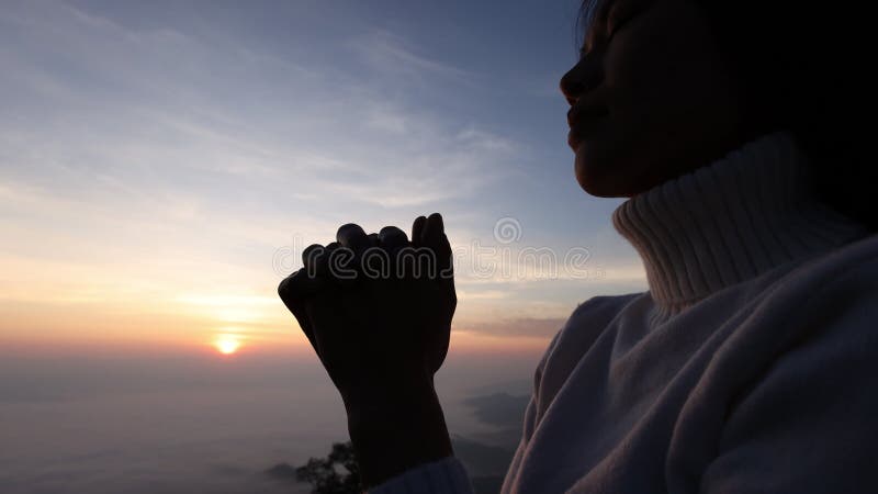 Silhouette van christelijke vrouw die 's ochtends bidden op de achtergrond van zonsopgang. spiritualiteit en religie